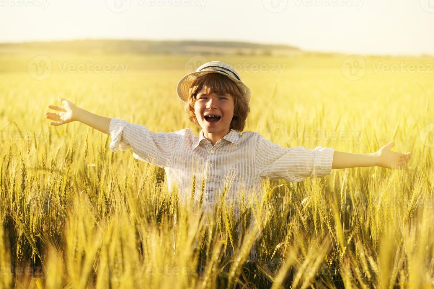 menino feliz no meio do campo de trigo foto