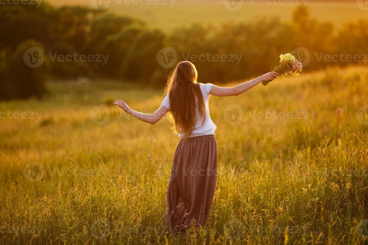 mulher feliz no campo com um buquê de flores foto