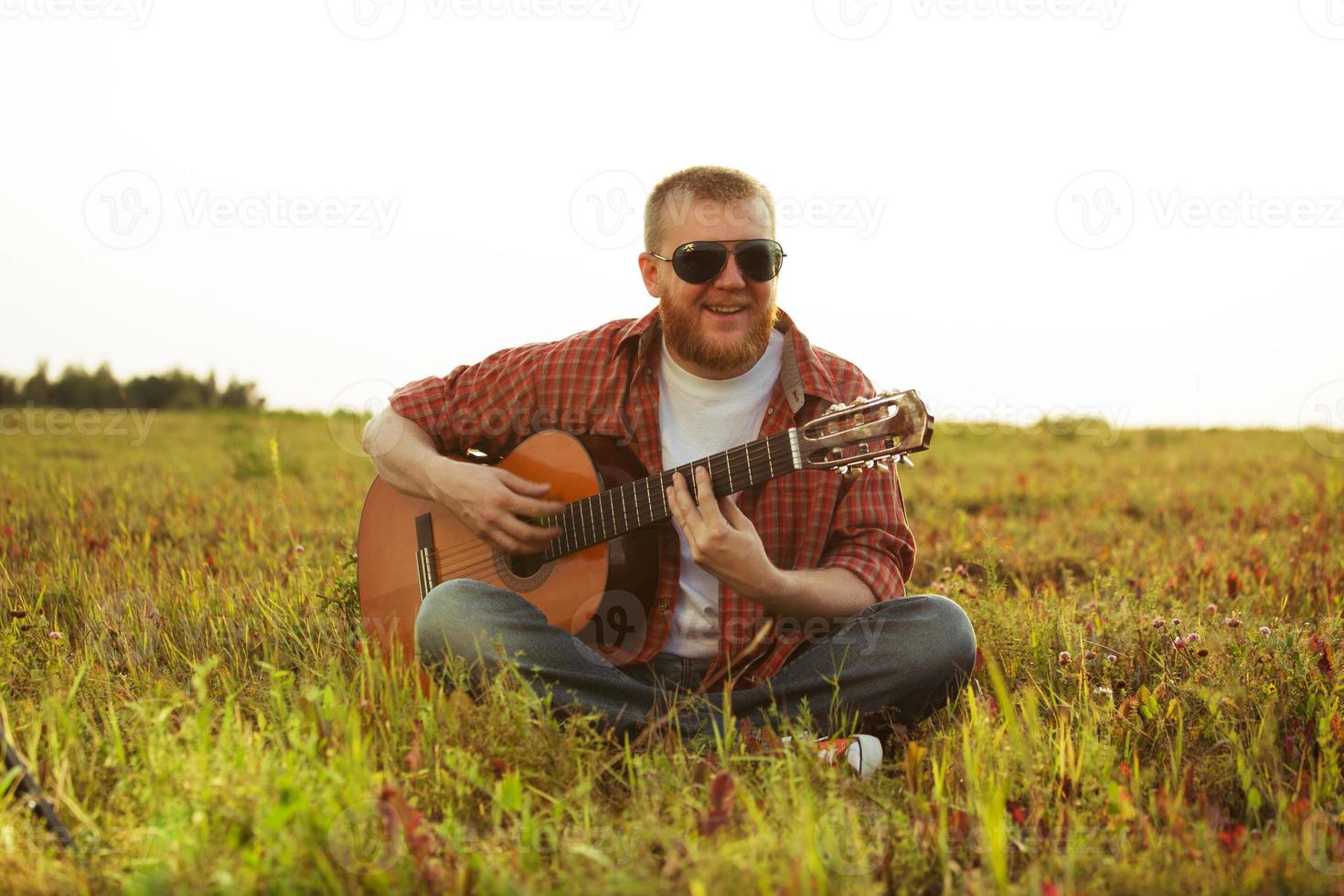 homem de jeans senta e toca violão foto