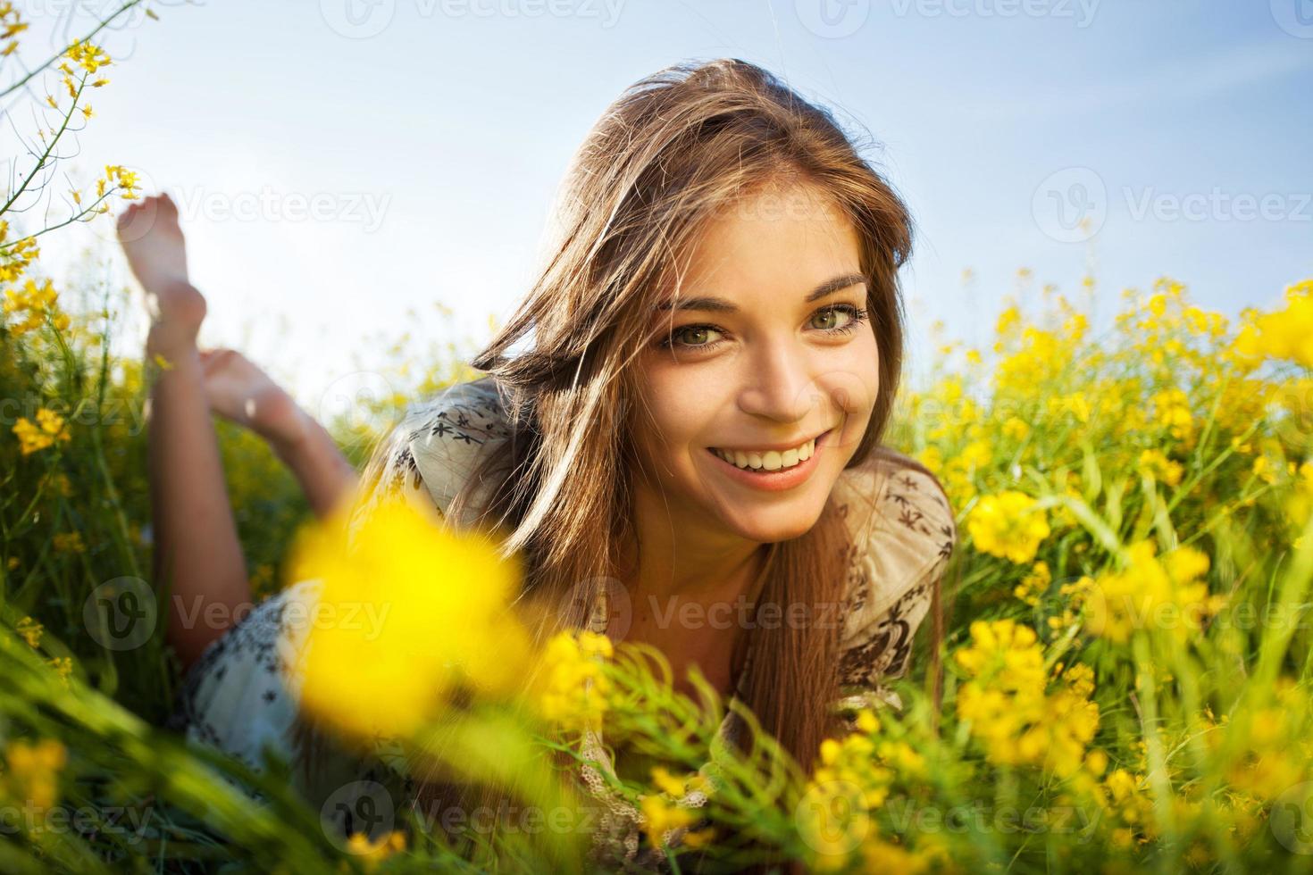 garota feliz deitada entre flores silvestres amarelas foto