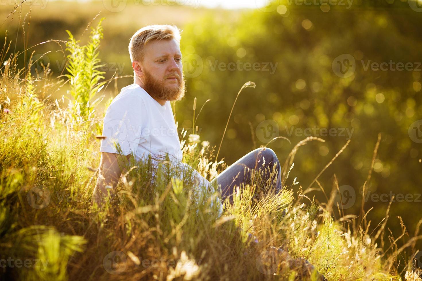 homem de barba vermelha sentado na grama foto