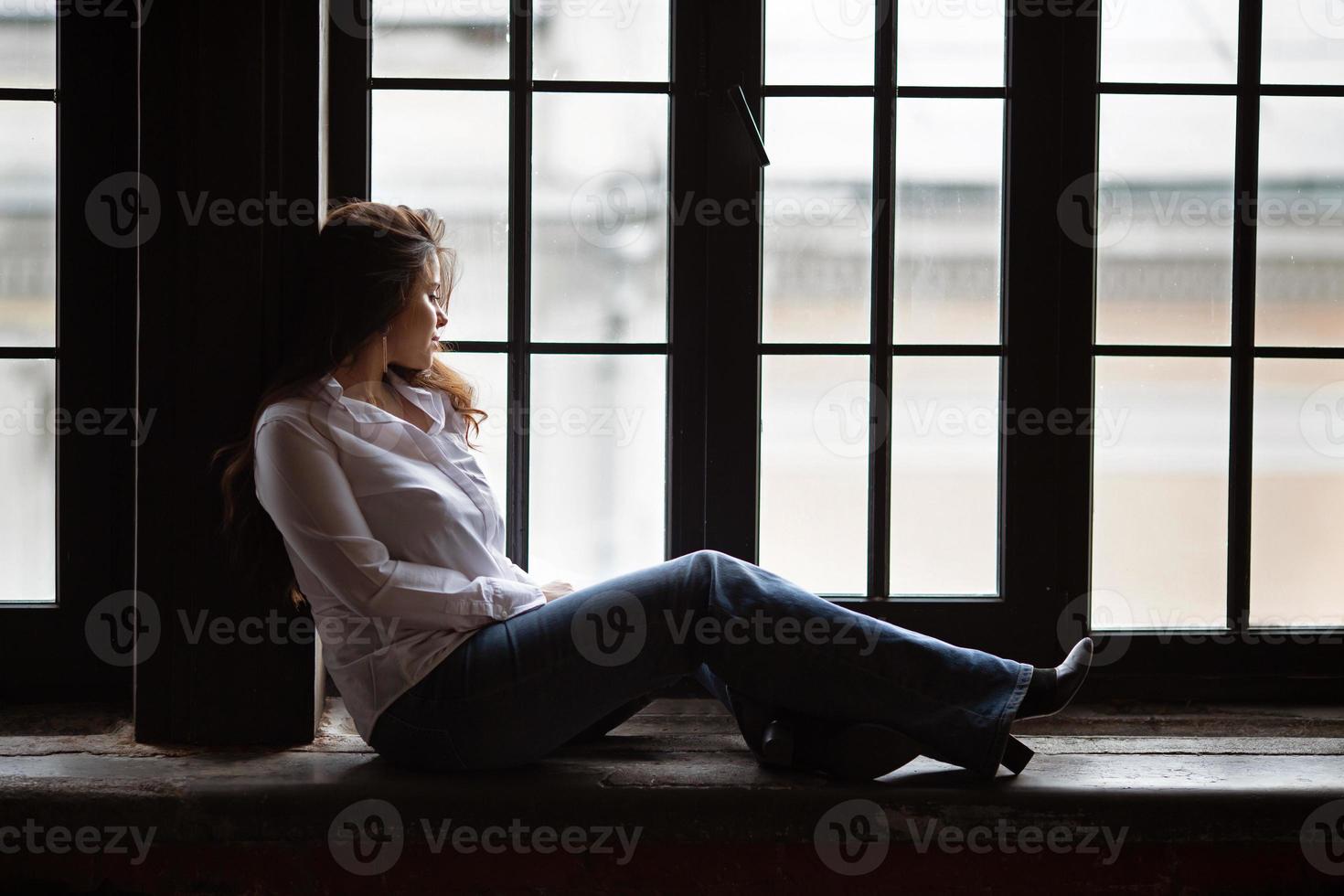 linda garota senta na janela e olha para fora foto