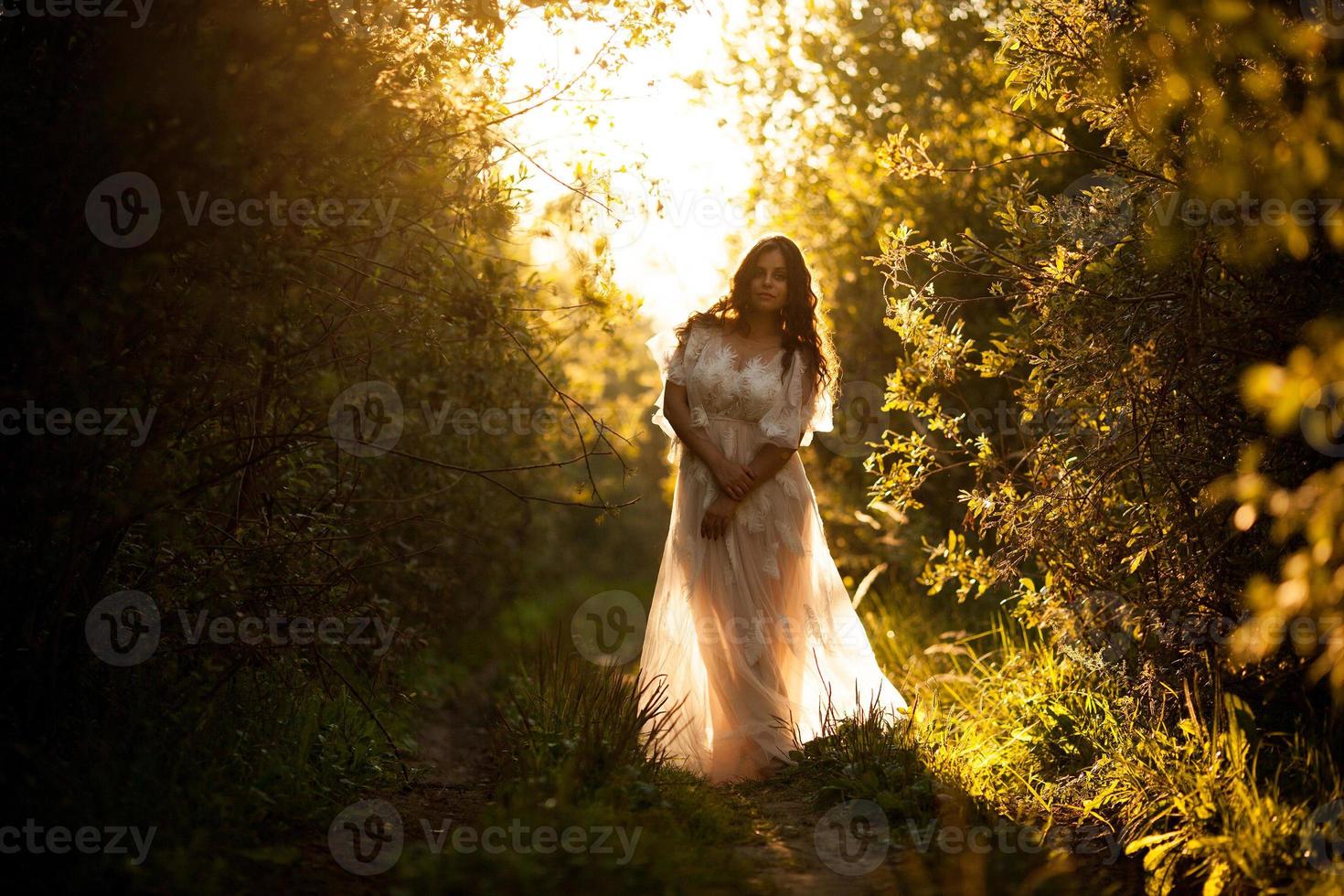 linda mulher em um vestido branco ao pôr do sol foto