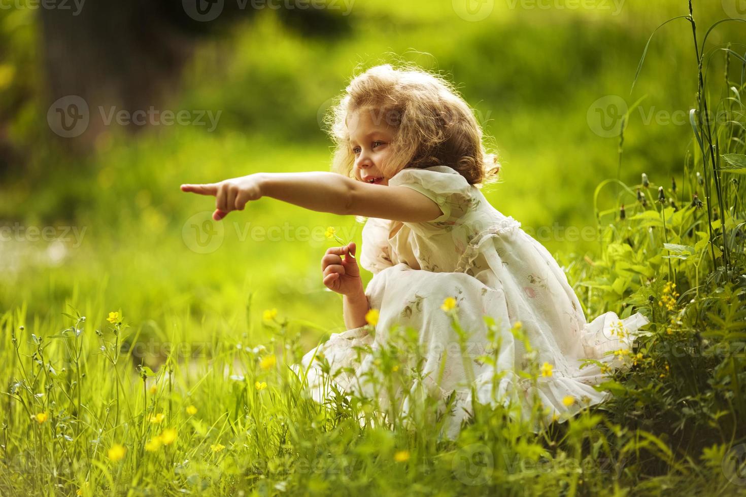 menina com uma flor indica algum lugar com a mão foto