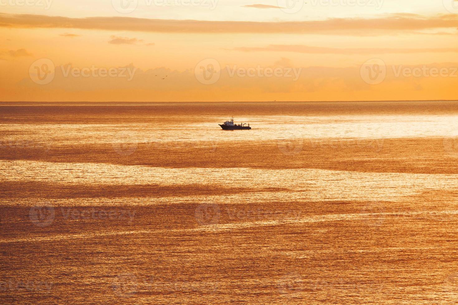 o navio está navegando no oceano ao nascer do sol foto