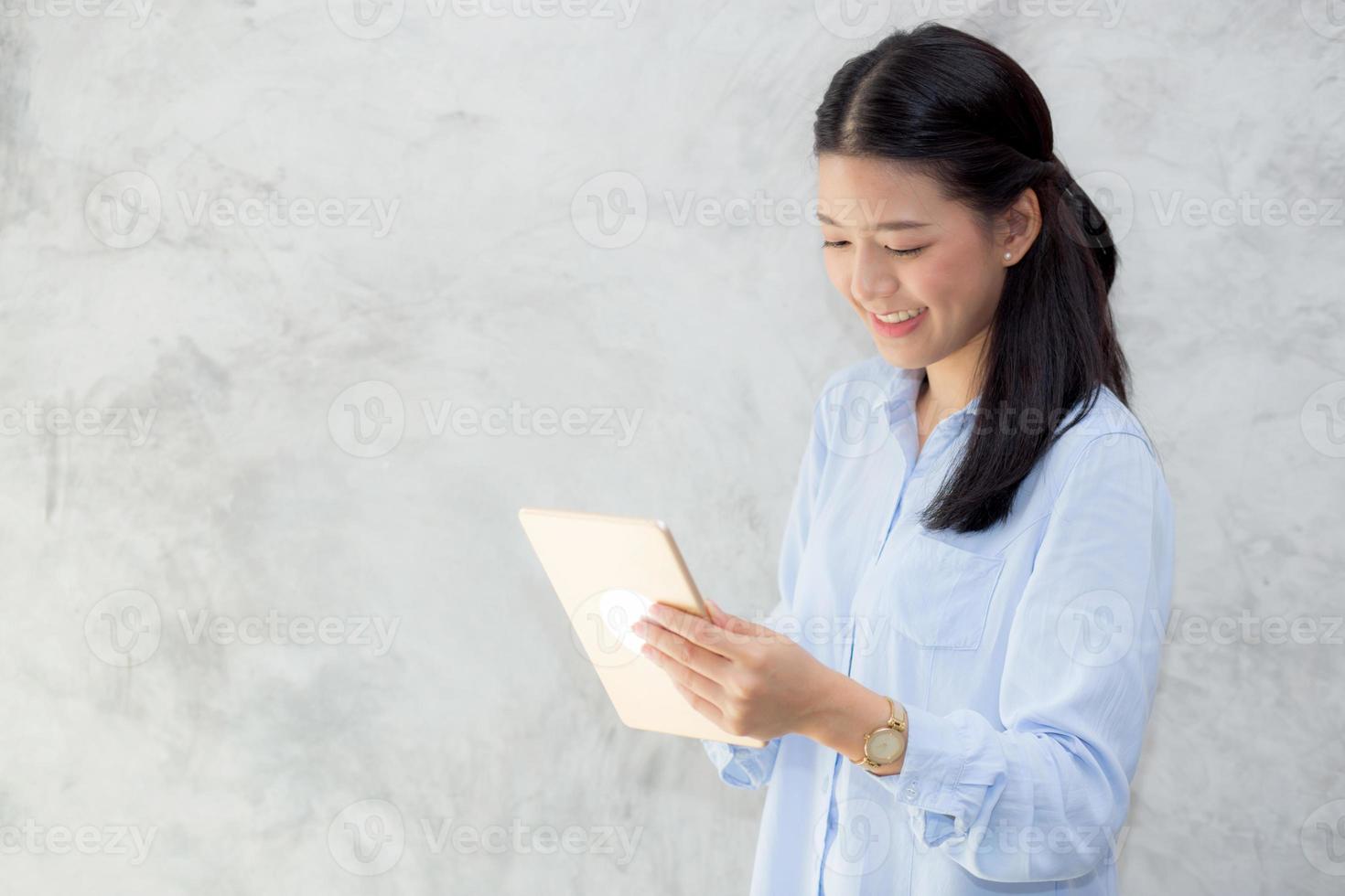 jovem mulher asiática tocar computador tablet e sorrindo. foto