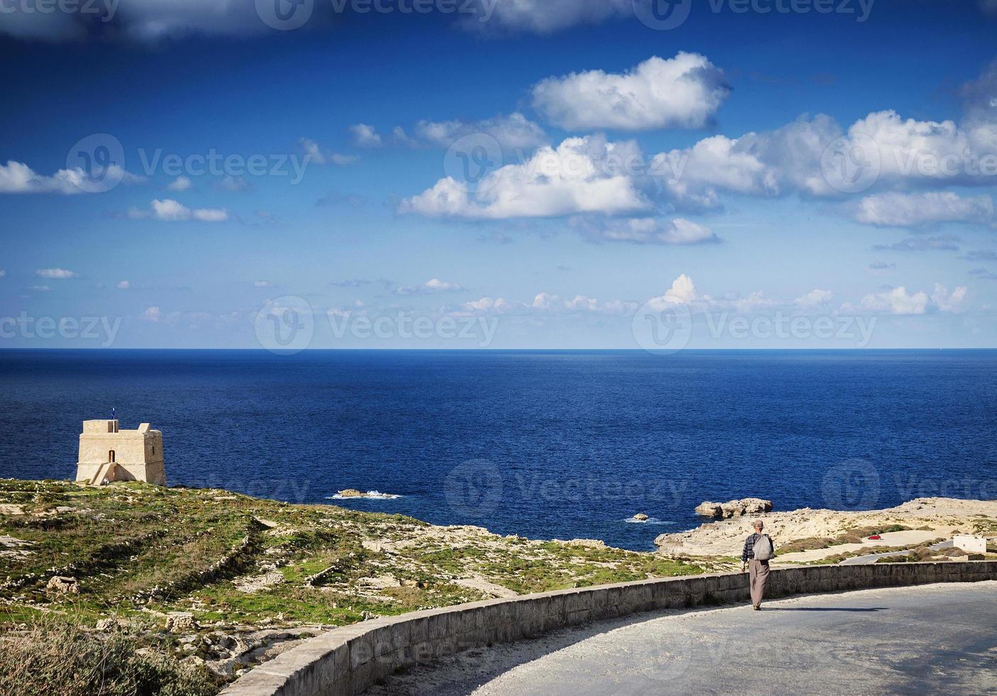 pastor na estrada perto do forte e vista da costa mediterrânea da ilha de gozo em malta foto