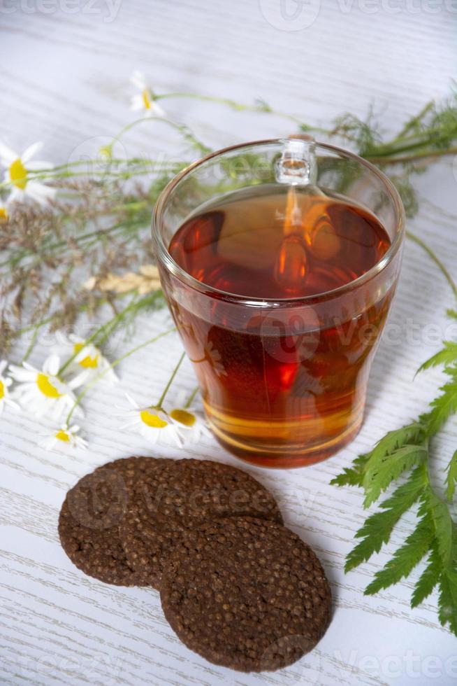 chá com biscoitos e camomila. copo de vidro com água quente foto