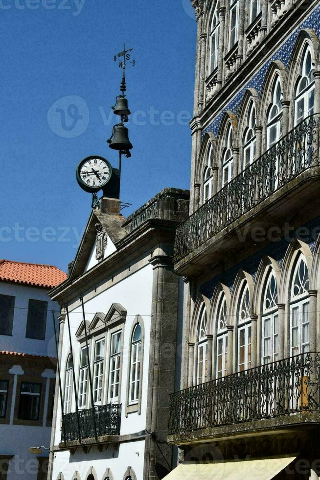 uma relógio em a lado do uma construção dentro uma cidade foto