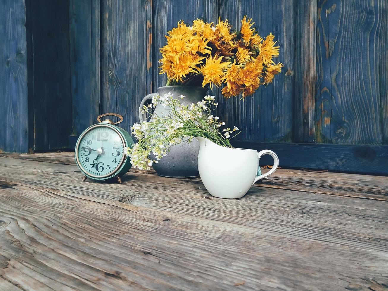 flores amarelas e relógio em fundo azul rústico foto