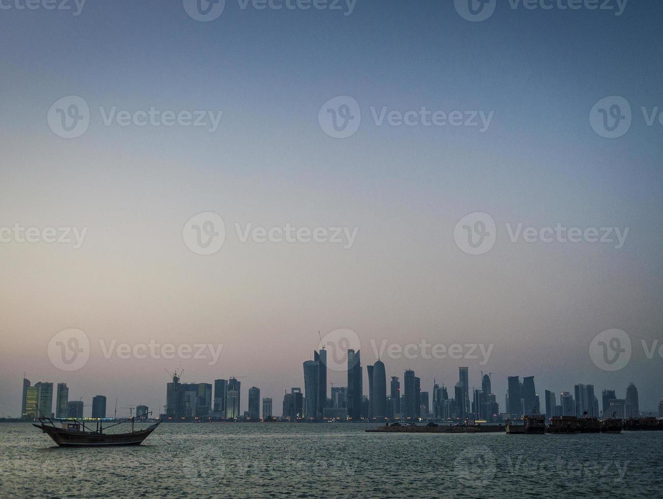 vista do horizonte urbano dos arranha-céus da cidade de Doha e barco dhow no Catar foto