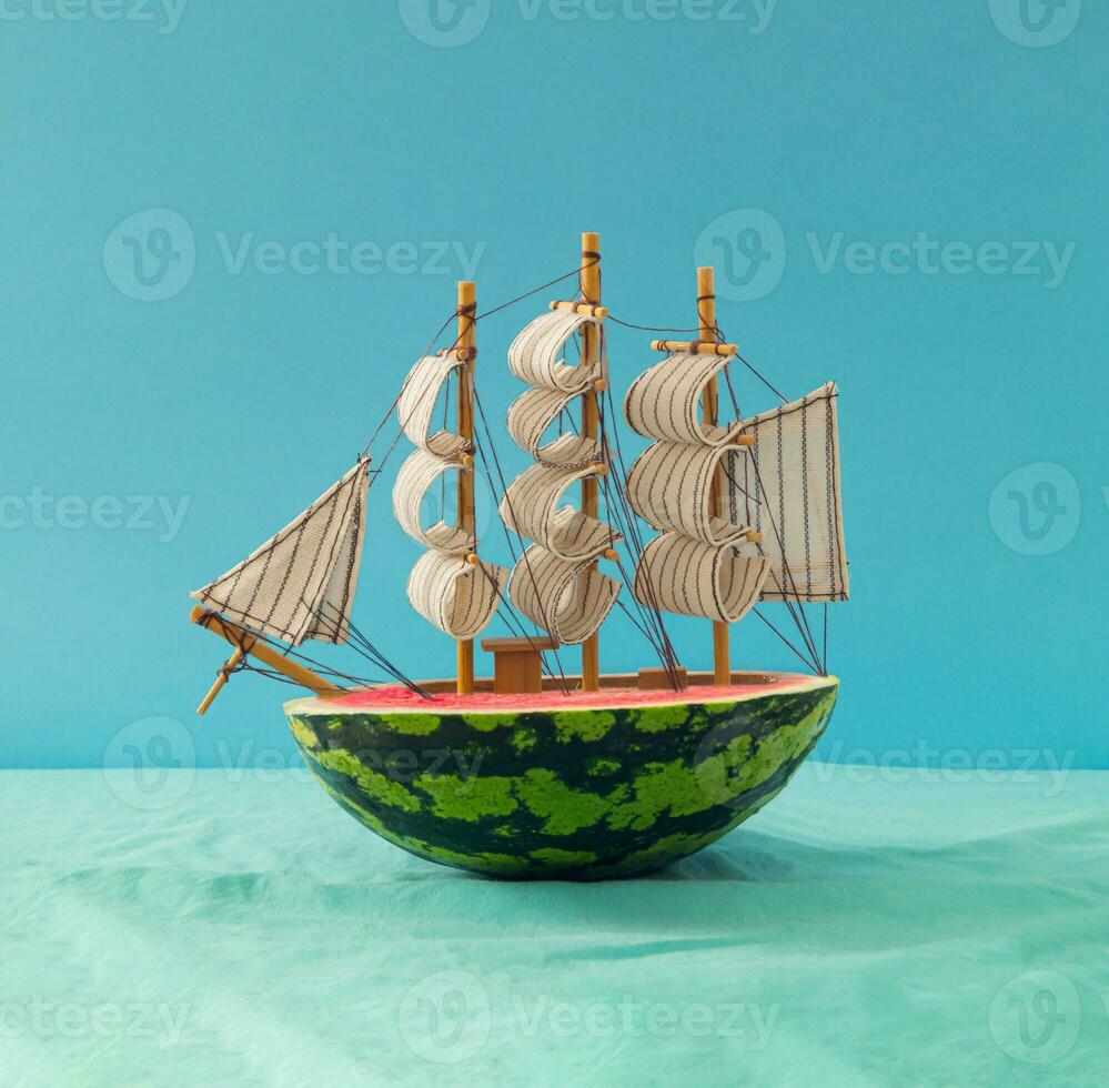 Melancia barco a vela viajando às a oceano. mar navio fez do Melancia contra azul fundo. mínimo viagem, período de férias e verão viagem conceito. criativo Comida ideia. verão fruta estética. foto