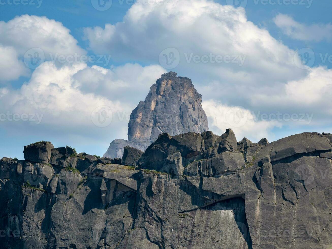 montanha pico dentro branco nuvens. a pico sobe entre a branco nuvens. dentro a fundo uma profundo azul céu e a Sol Aumentar através a nuvens. foto