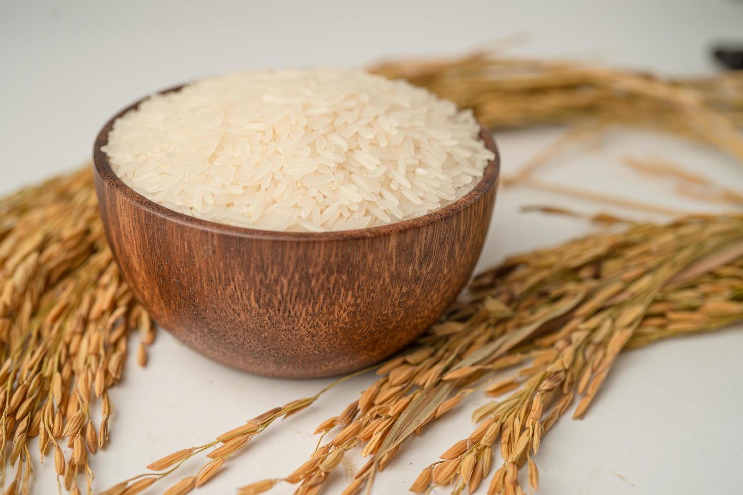 arroz branco jasmim em tigela de madeira com grão de ouro foto