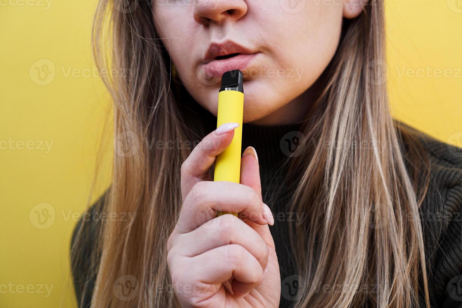 uma jovem fuma cigarro eletronico descartável foto