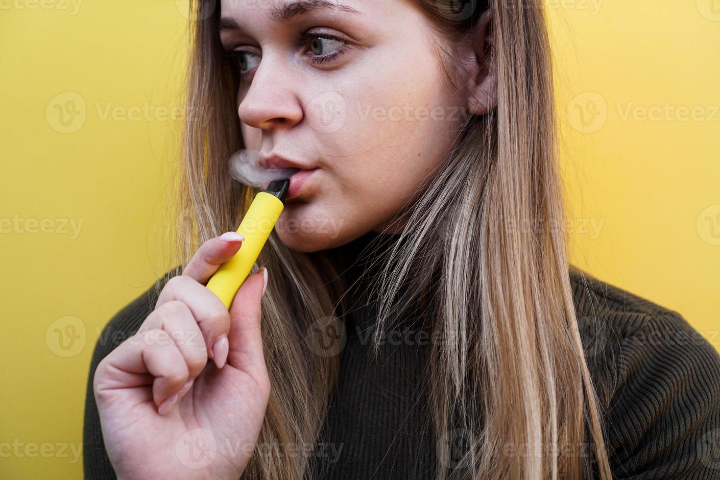 uma jovem fuma cigarro eletronico descartável foto