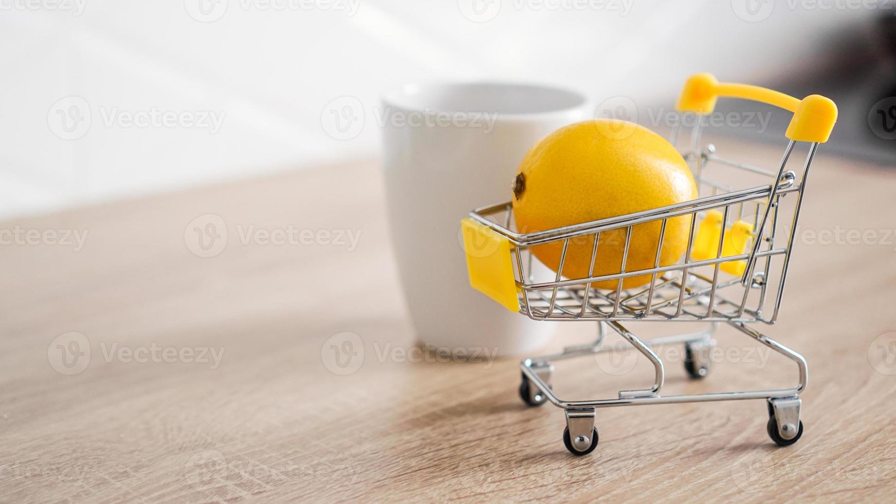 limão em um pequeno carrinho de compras na mesa da cozinha foto