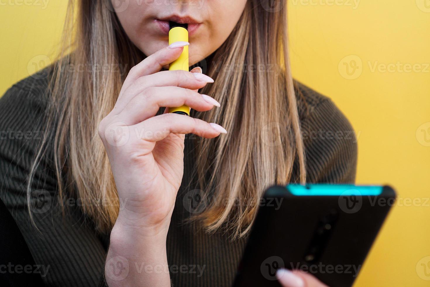 uma jovem fuma cigarro eletronico descartável foto