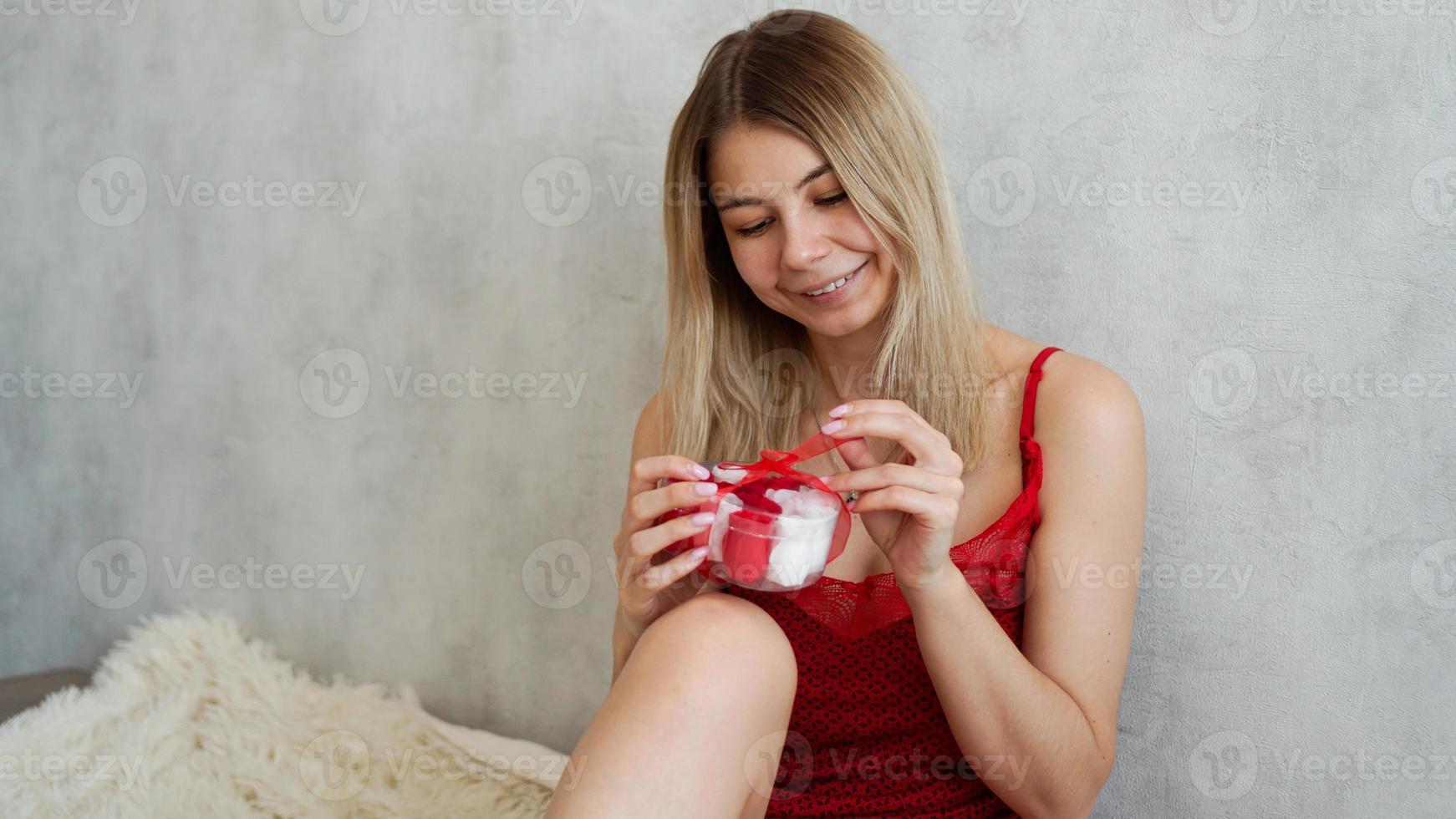 retrato de uma linda garota recebe uma caixa de presente, desfrutando de um presente em casa foto