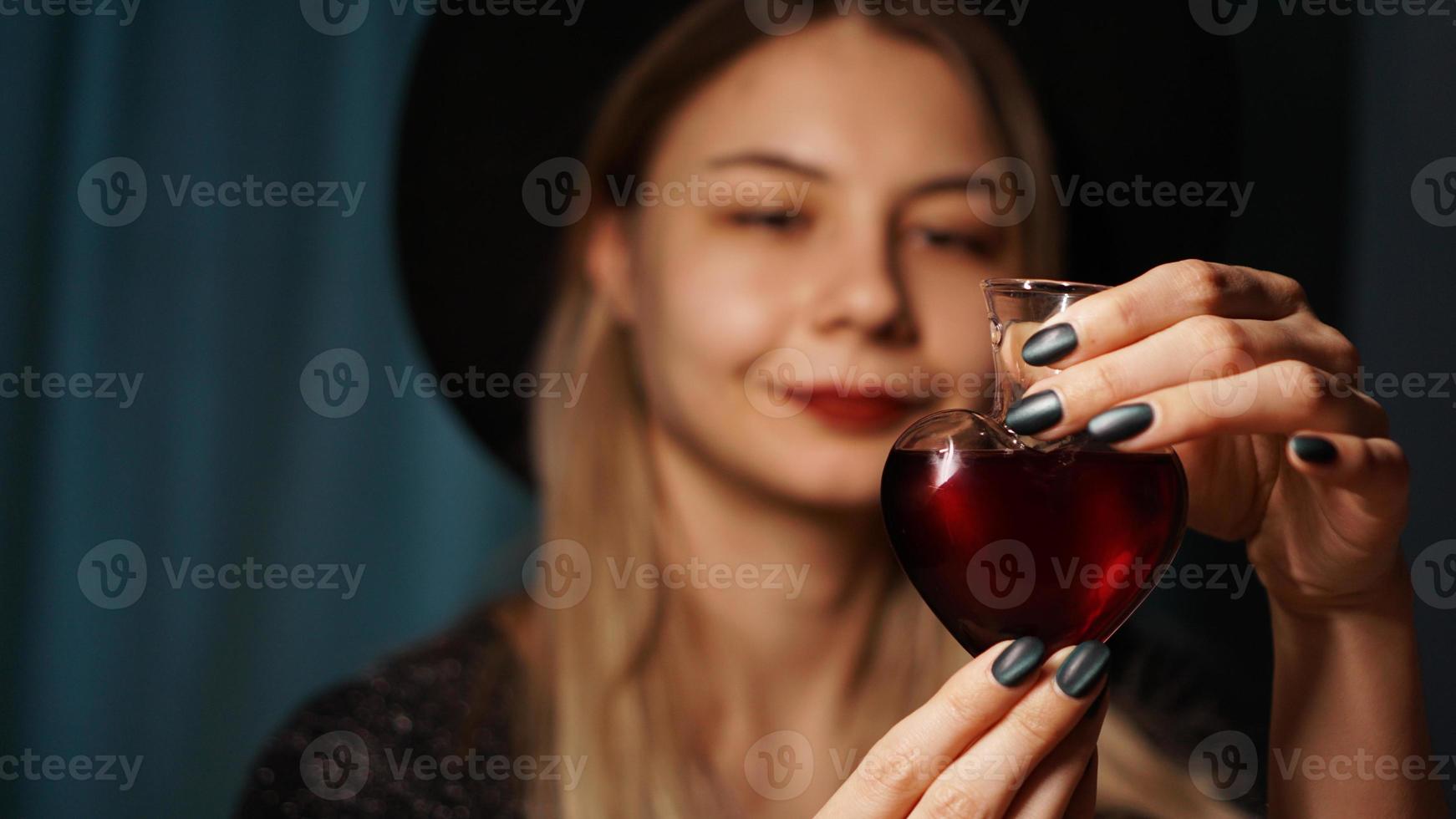 imagem recortada de mulher segurando um frasco de vidro em forma de coração com poção do amor foto