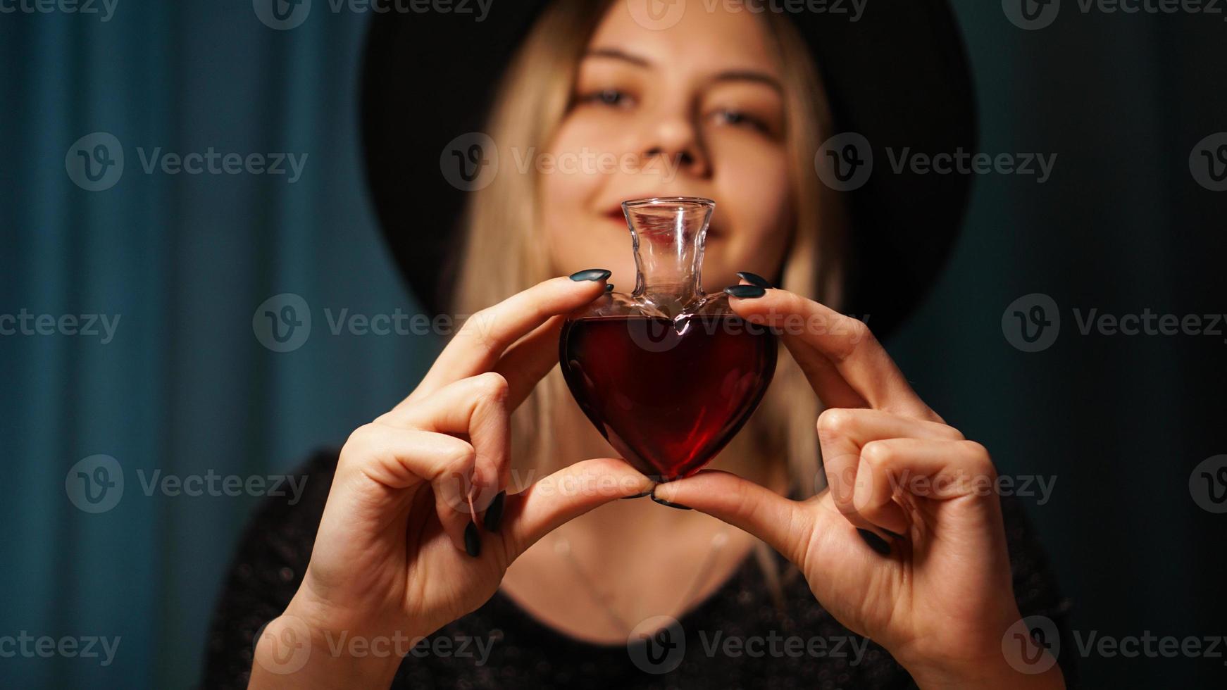 imagem recortada de mulher segurando um frasco de vidro em forma de coração com poção do amor foto