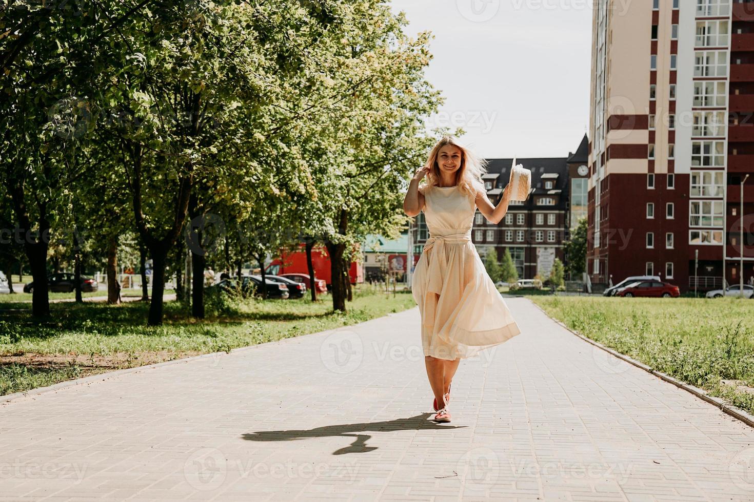 uma bela loira caminha por uma cidade. mulher de vestido branco foto