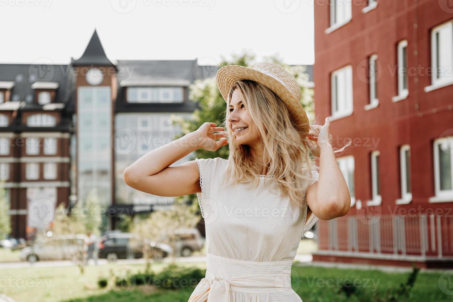 uma bela loira caminha por uma cidade. mulher de vestido branco foto