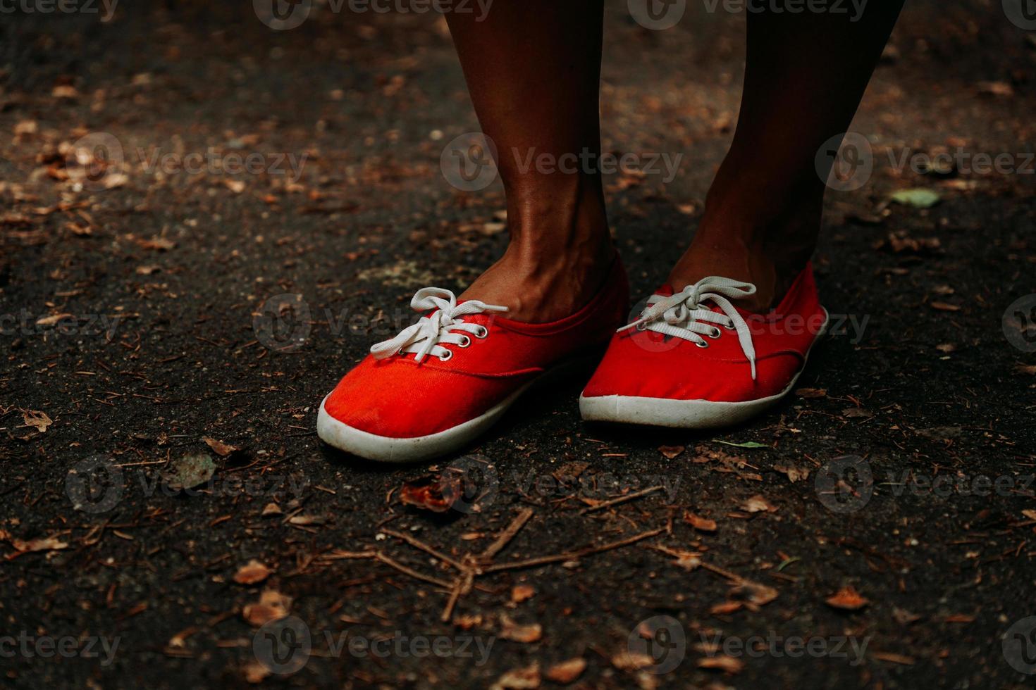pernas de tênis vermelhos em um caminho de outono no parque. pernas de couro preto foto