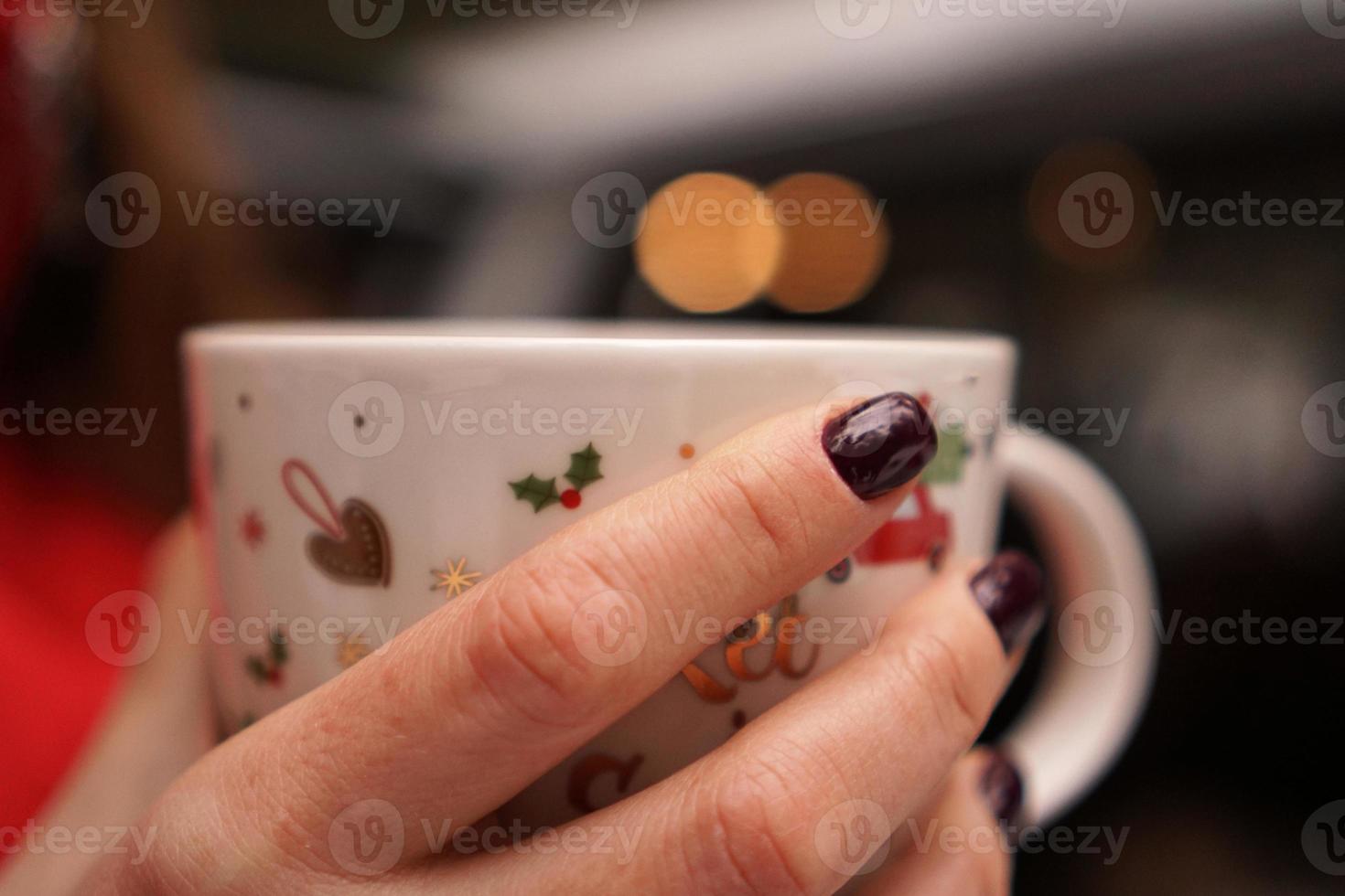 mãos femininas segurando um copo com uma bebida quente e escura do lado de fora no dia de inverno foto