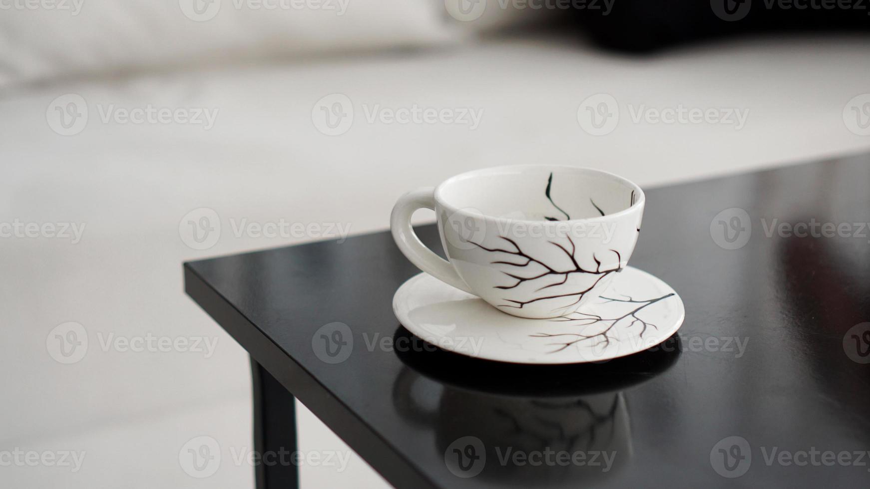 xícara de café branca com um padrão de galhos pretos em uma mesa preta foto