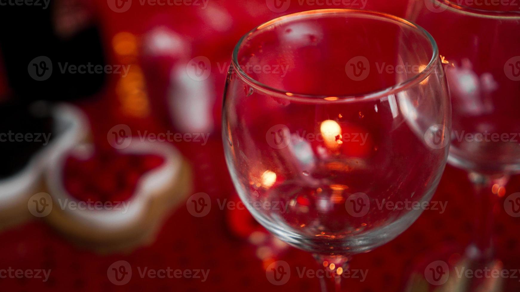 copo de vinho vazio no jantar de amor, vela no fundo vermelho foto