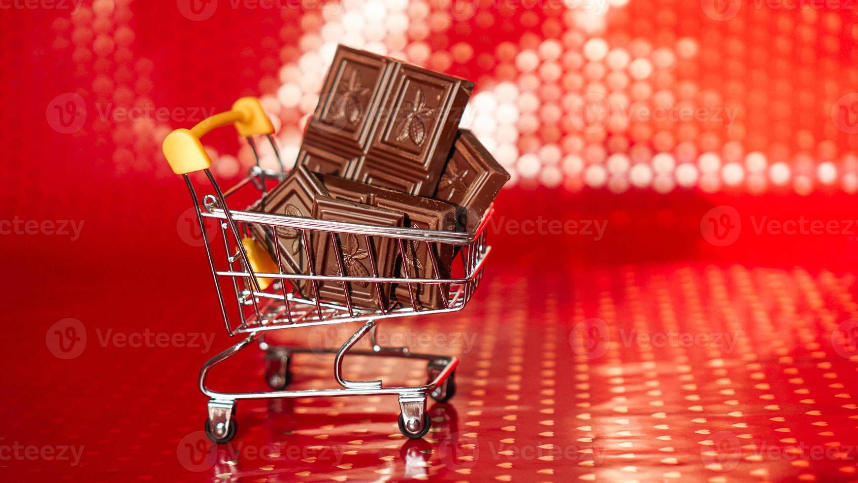 chocolate no carrinho de compras em fundo vermelho. Venda de 14 de fevereiro foto