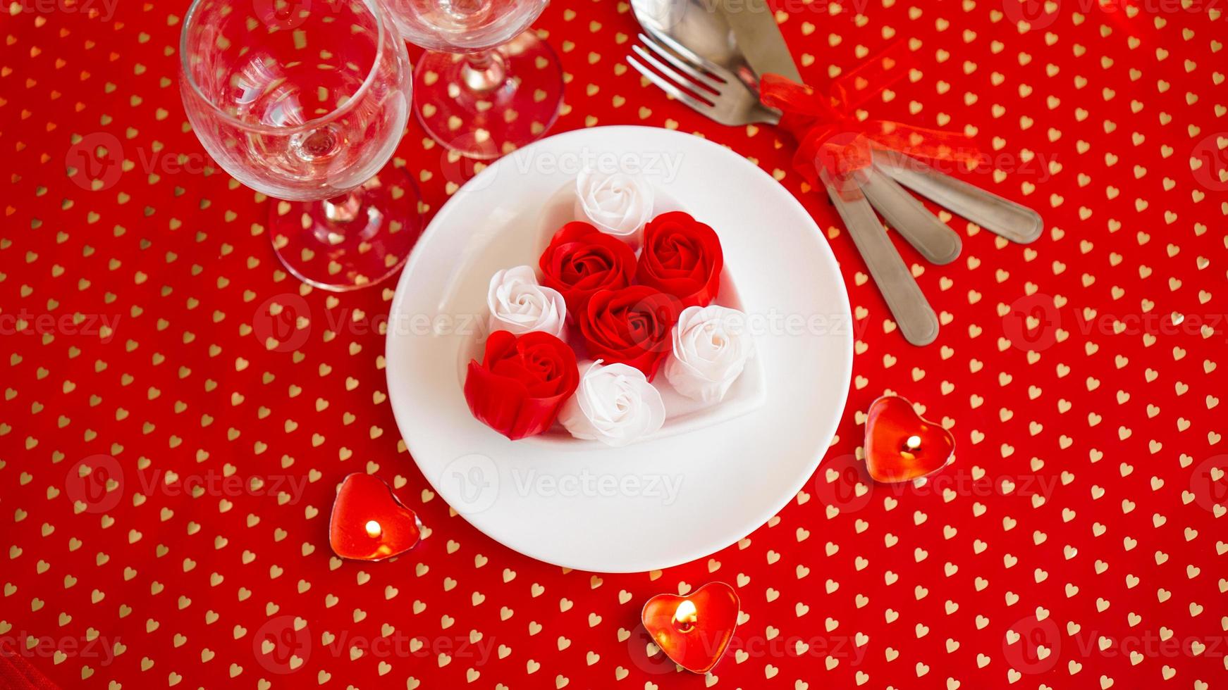 um prato branco com uma faca e um garfo em um fundo vermelho brilhante foto