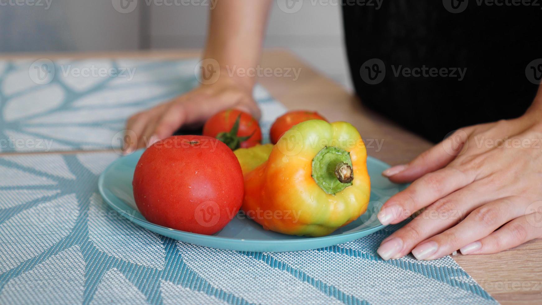 tomate e pimenta em um prato azul sobre um fundo claro na cozinha foto