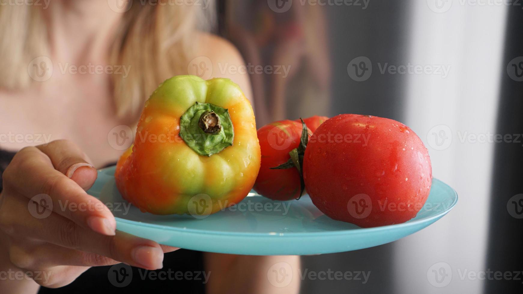 mulher segurando o prato com legumes frescos foto