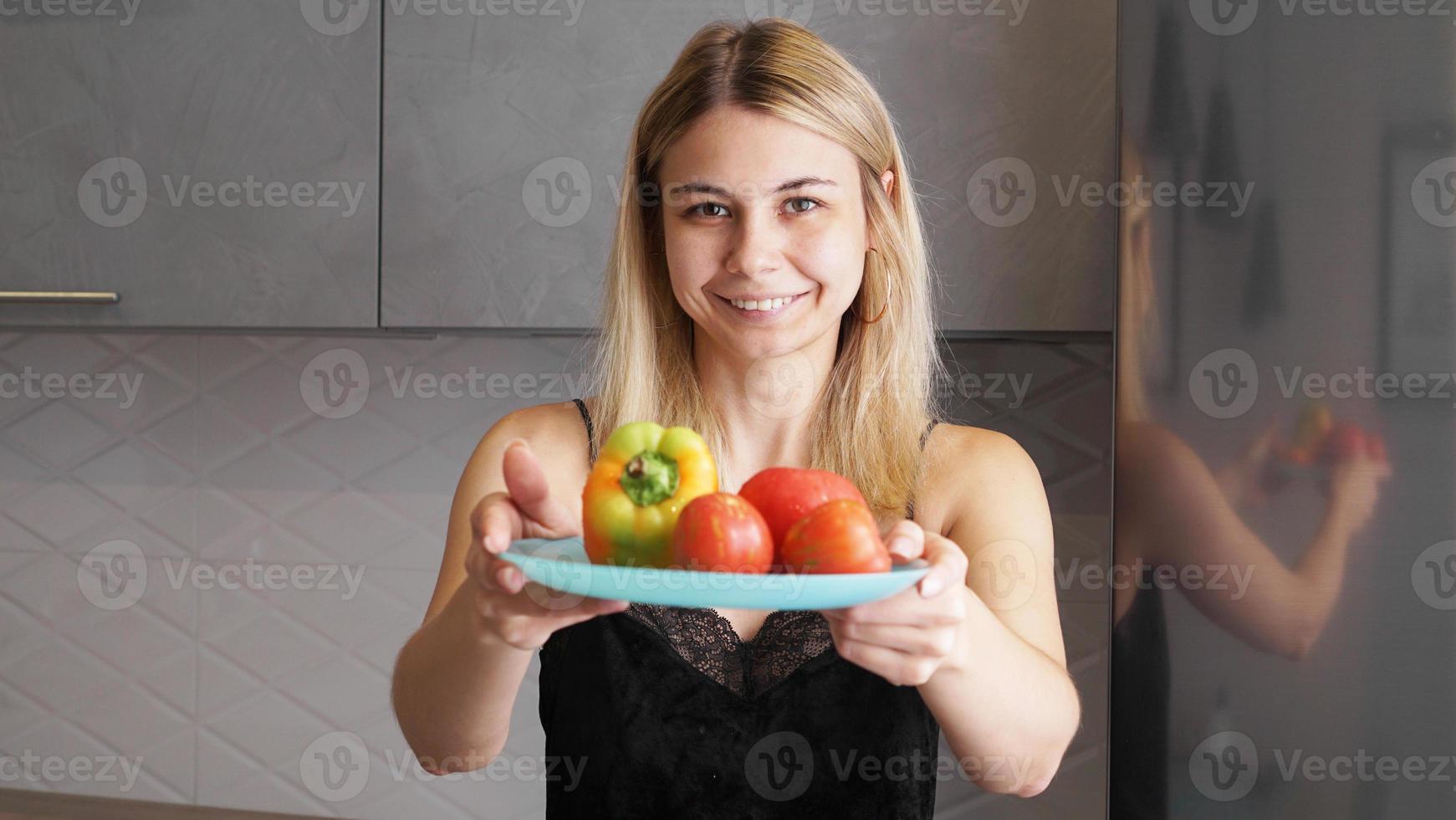 mulher segurando o prato com legumes frescos e sorrindo foto