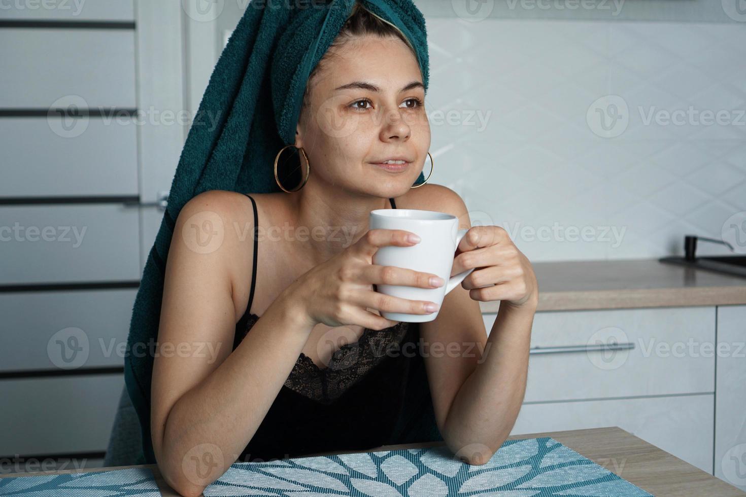 Mulher bonita sentada na cozinha com uma xícara de café foto