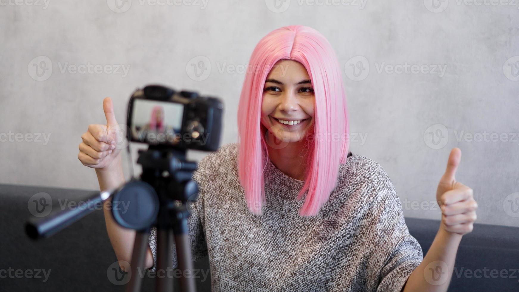 wwoman ou blogger com câmera gravando vídeo e mostrando o polegar para cima foto