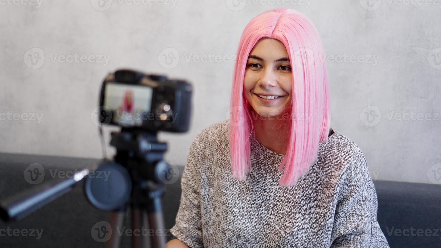 blogueira feliz com peruca rosa na frente da câmera em um tripé foto