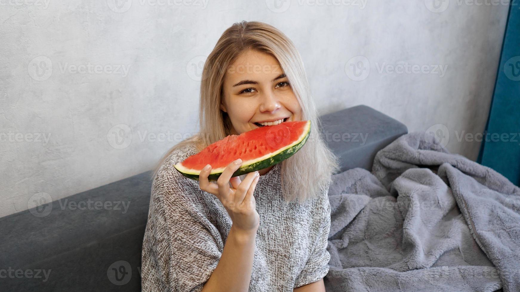 jovem mulher atraente comendo melancia. mulher em casa foto