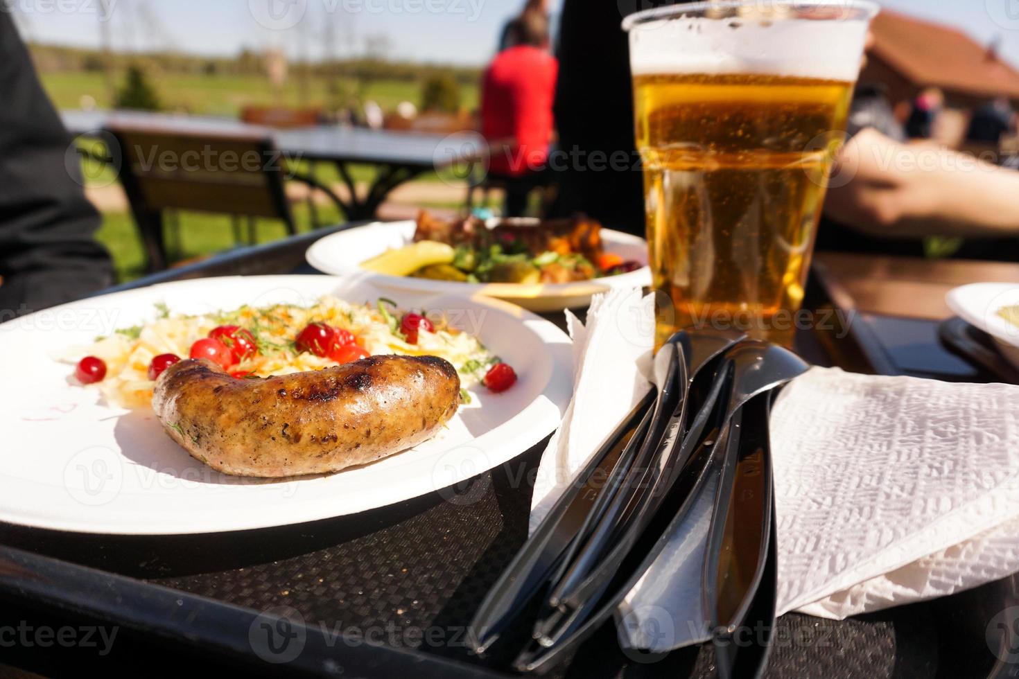 salsicha com salada no prato e cerveja light na bandeja. comida de rua foto