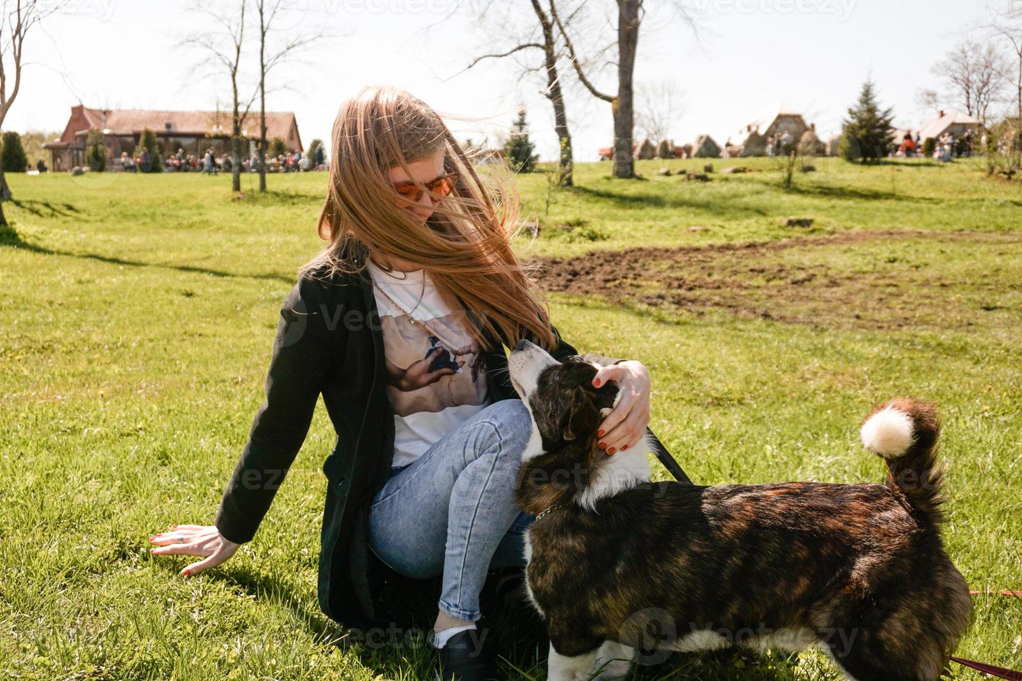 jovem de óculos de sol vermelhos brincando com seu corgi foto