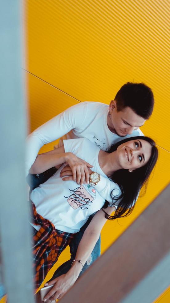 jovem casal adorável posando juntos e se abraçando sobre um fundo amarelo foto