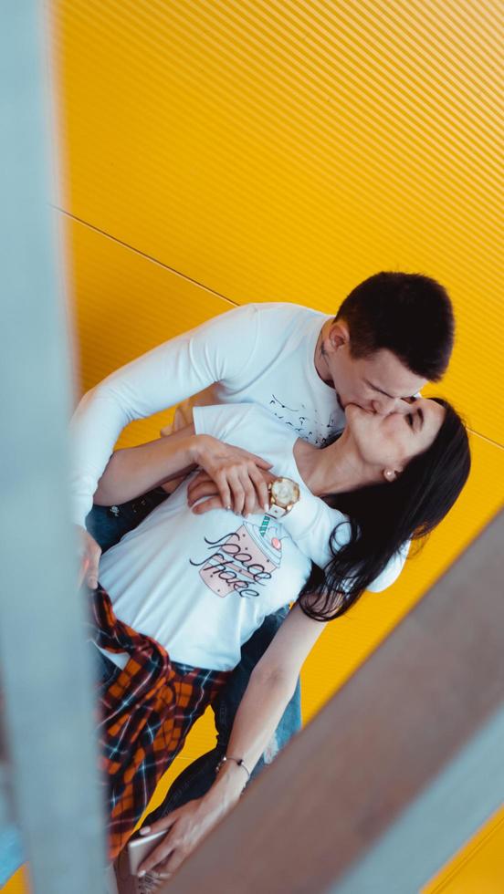 jovem casal adorável posando juntos e se abraçando sobre um fundo amarelo foto