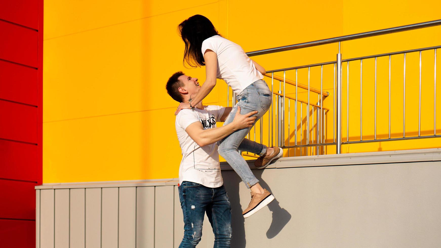 homem feliz carregando sua namorada em fundo amarelo foto