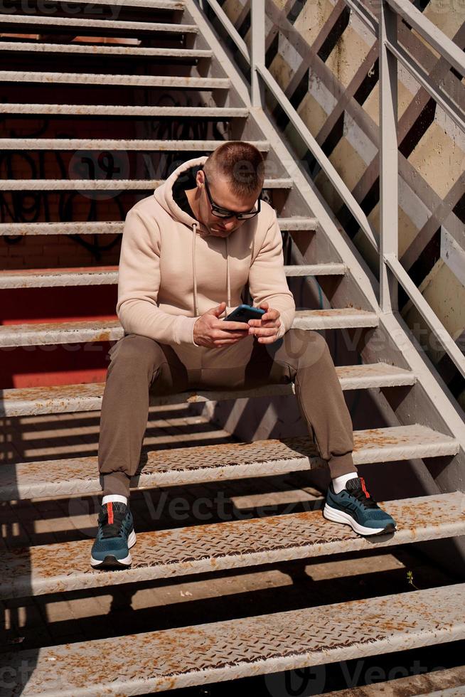 um jovem se senta na escadaria da cidade. estilo urbano foto