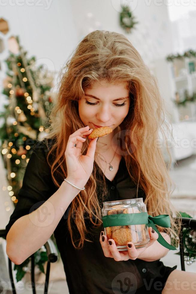 jovem feliz comendo biscoitos de natal na cozinha foto