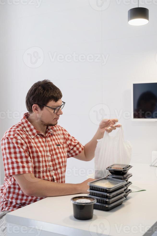 jovem separando caixas de entrega de comida na cozinha moderna foto