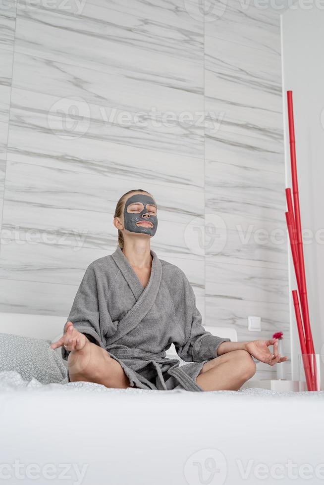 mulher com máscara facial relaxando sentada na cama foto