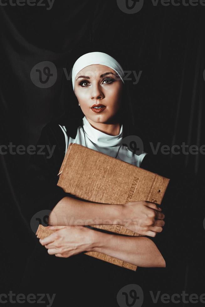 bela jovem freira em terno preto religião detém a Bíblia. religião foto